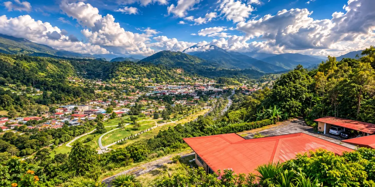 A view from a slope over a town in a green basin, a red metal roof in the foreground