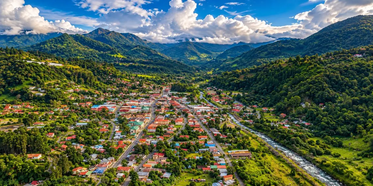 A mountain town from above: metal roofs, the main street, a river along the edge of the valley