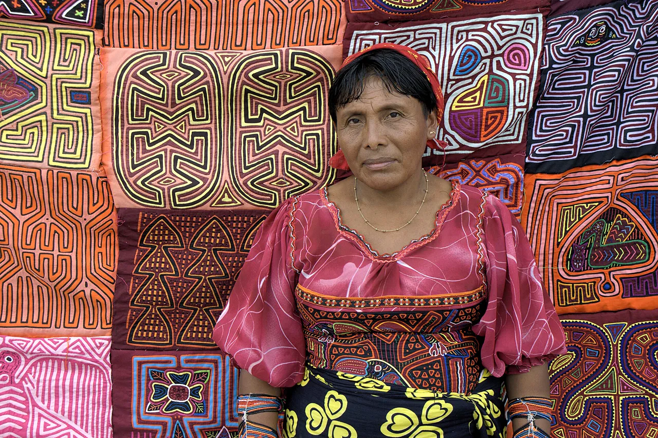A Guna woman in front of molas, brightly colored handmade panels