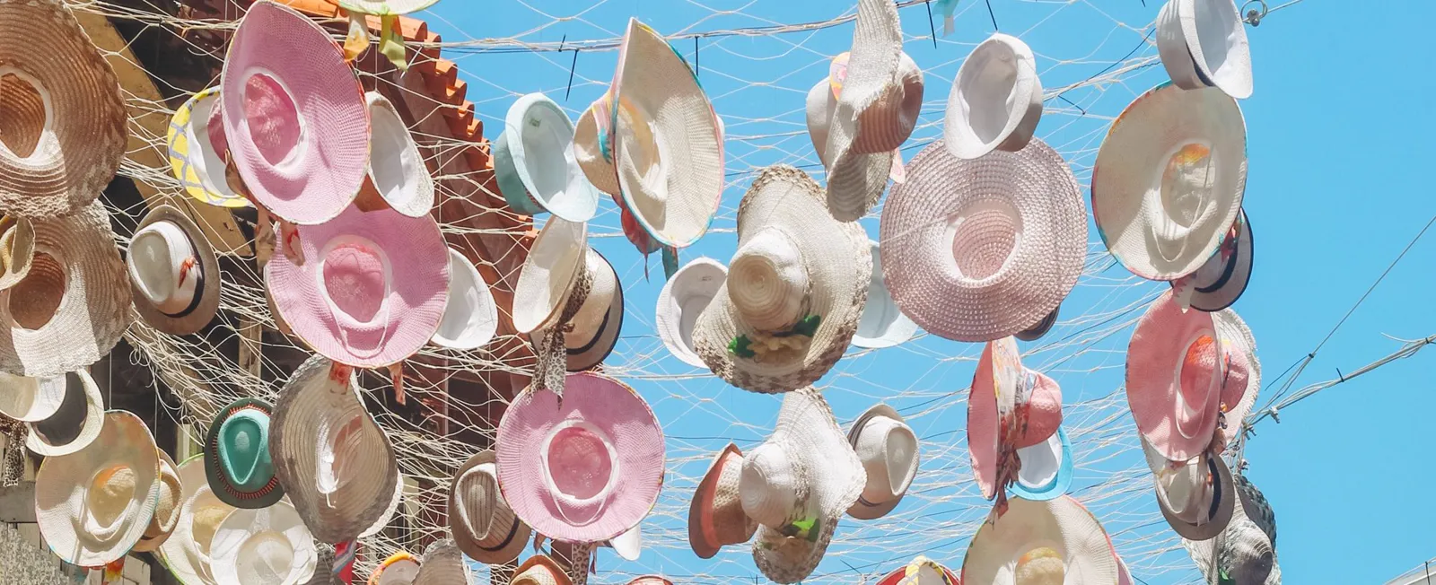 Dozens of straw hats against a blue sky