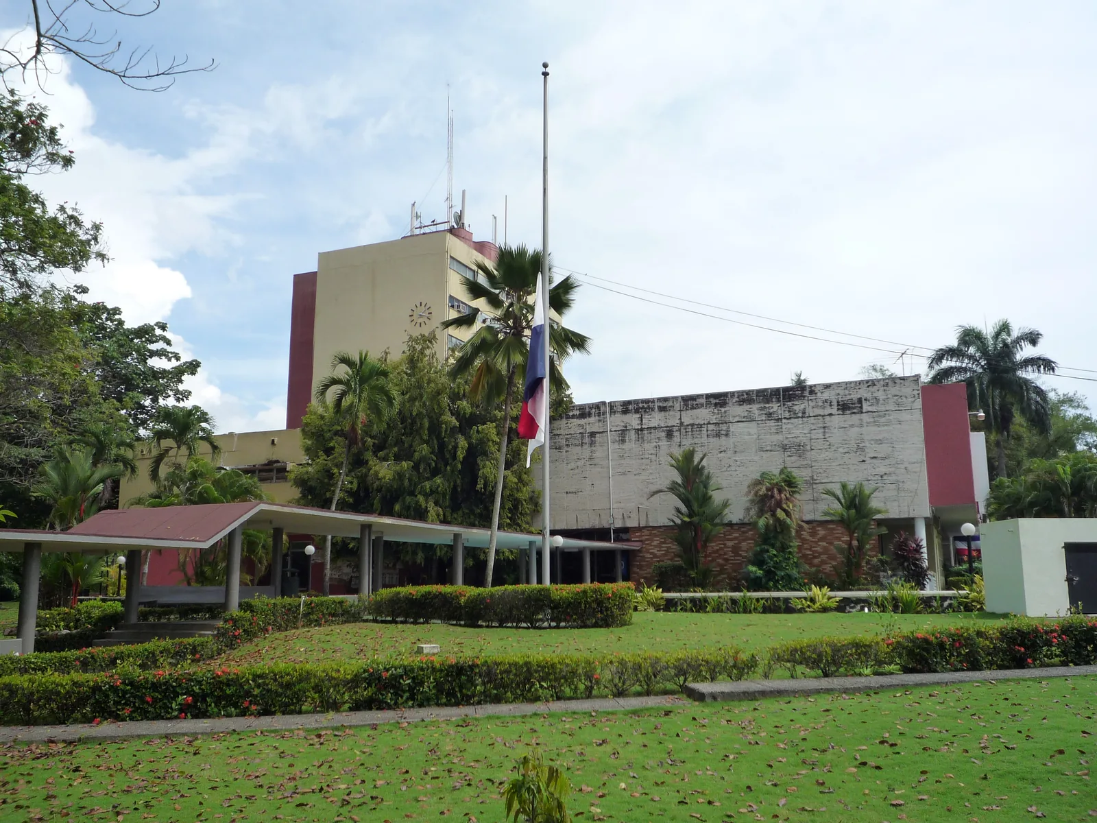 The main campus of the University of Panama: a clock-tower building and the Panamanian flag among palm trees