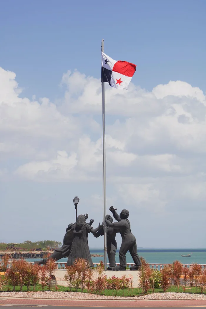 A monument: figures of people raising the flag of Panama by the sea