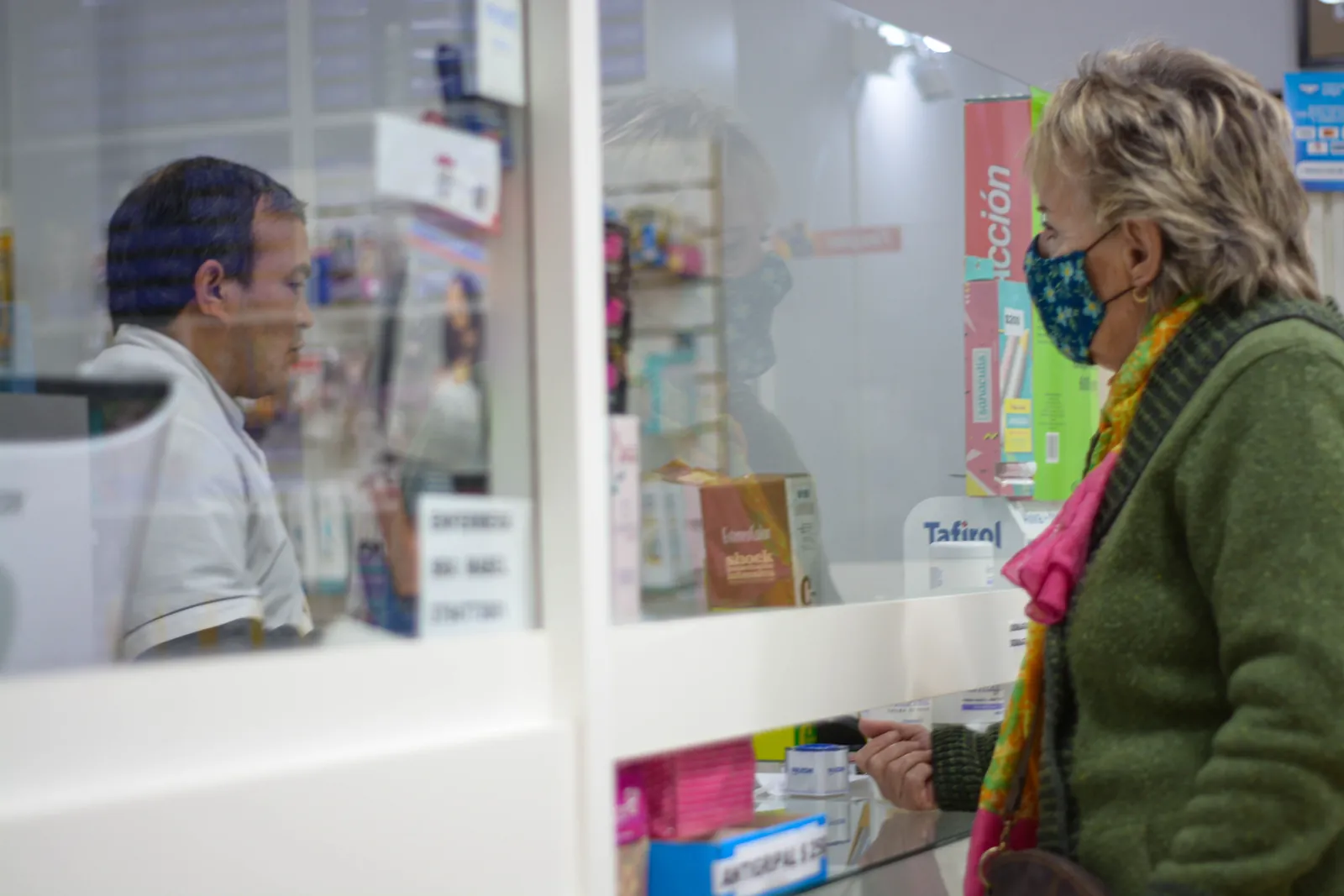 A customer at a pharmacy counter talking with the pharmacist