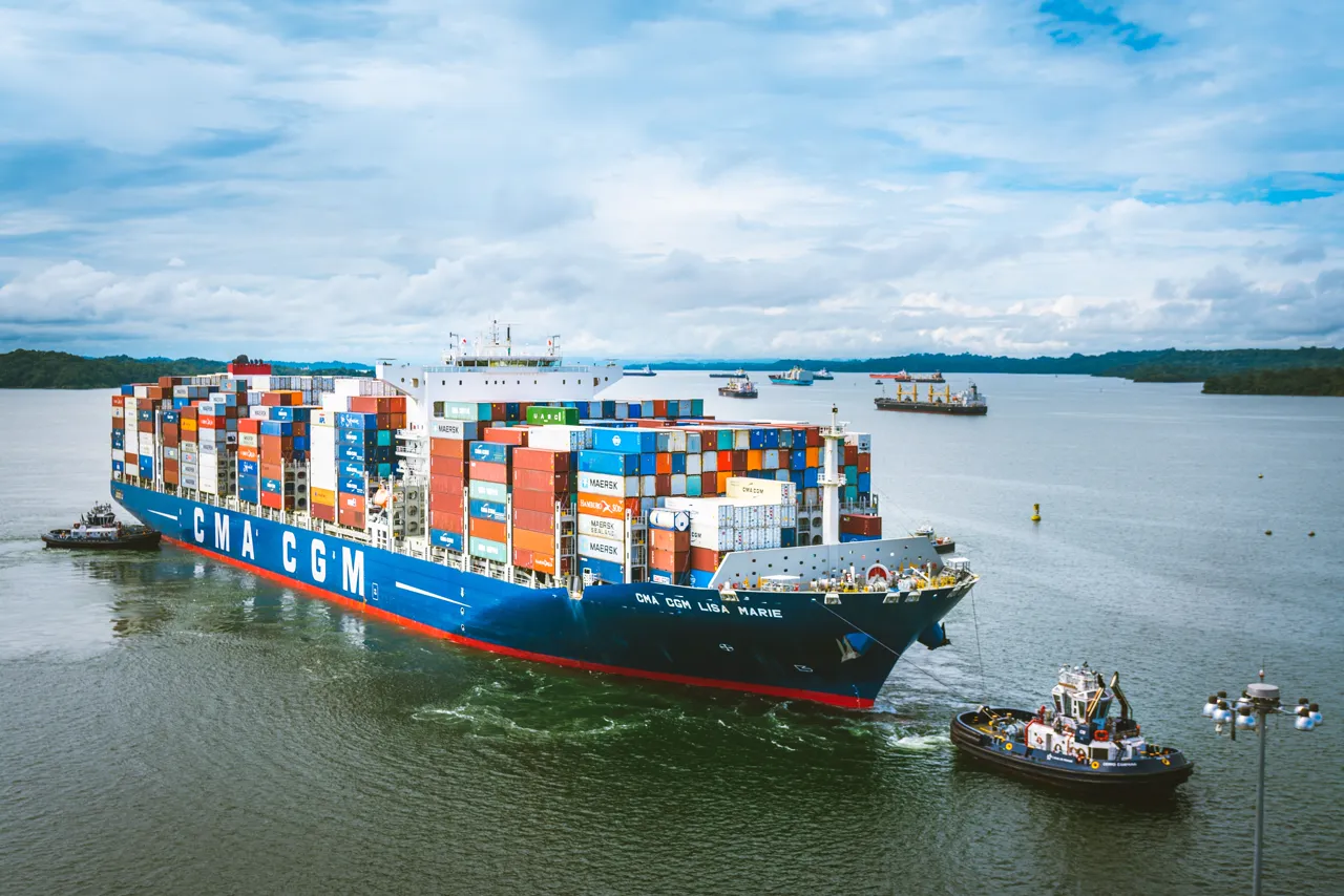 A container ship escorted by a tugboat passes through the Panama Canal