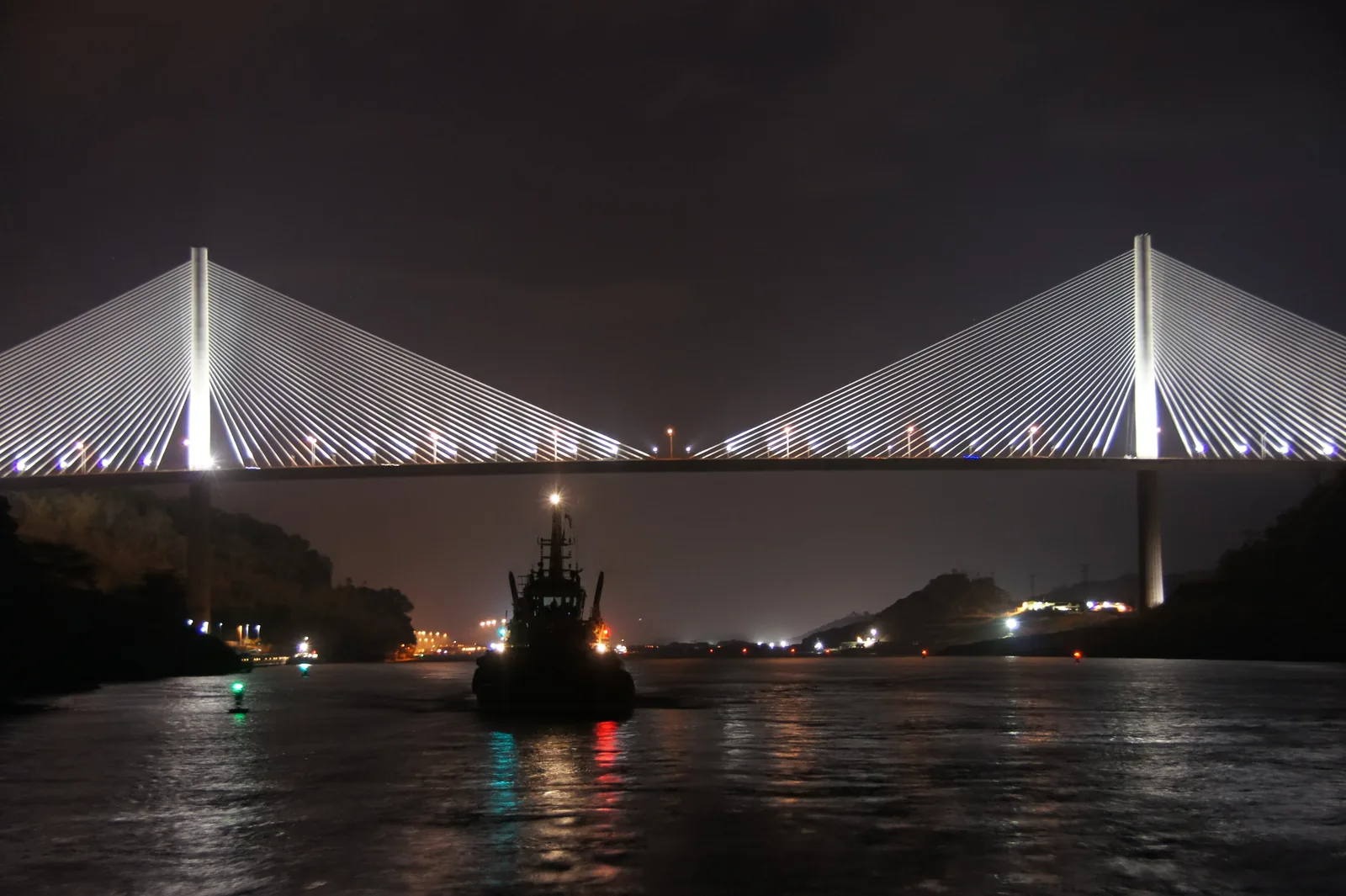 The Centennial Bridge at night: illuminated pylons and cables above the canal